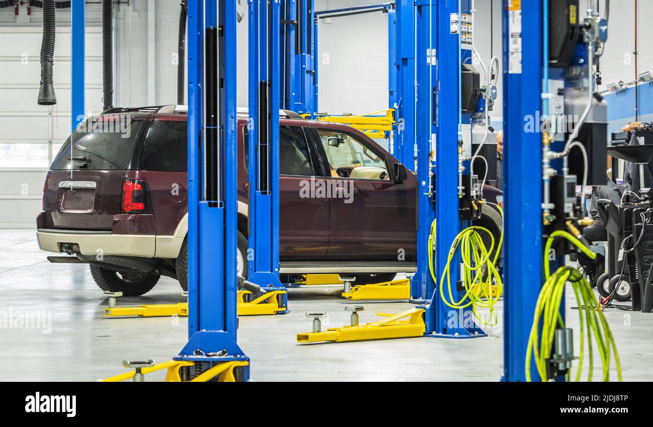 SUV Car on an Automotive Lift During Scheduled Maintenance. Authorized Repair Service. Automotive Industry Theme. Stock Photo