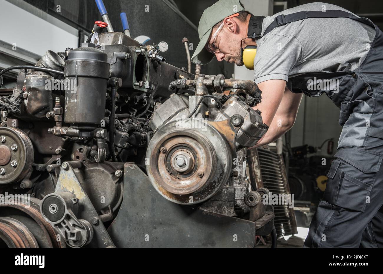 Rebuilding Heavy Duty Coach Bus Diesel Engine. Professional Caucasian Mechanic Taking Closer Look. Automotive Industry. Stock Photo