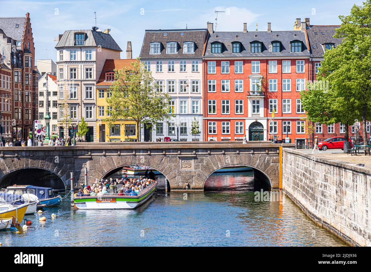 A tourist boat passing under the Stormbro bridge which marks the joining of the Slotsholmen Canal and Frederiksholm Canal in Copenhagen, Denmark. Stock Photo