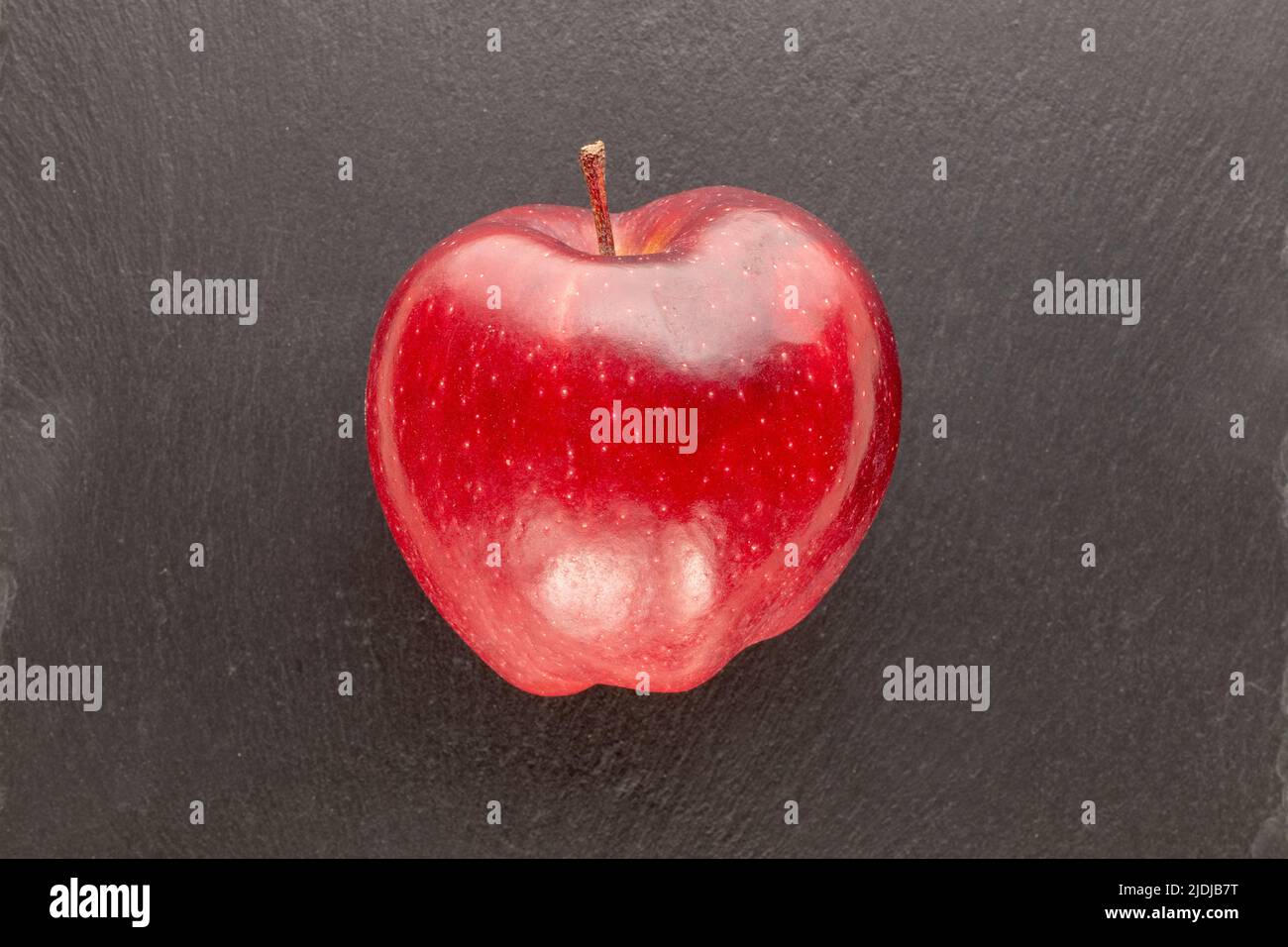 One ripe red apple on a slate stone, close-up, top view. Stock Photo