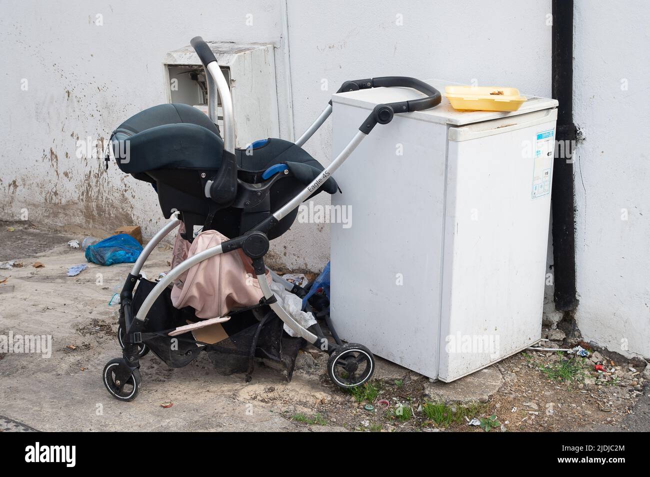 Slough, Berkshire, UK. 21st June, 2022. A child's pushchair and a fridge dumped on a street in Slough. Illegal fly tipping can result in fines of up £50,000 or 12 months imprisonment for those convicted of fly tipping. Slough has a big tip in Chalvey that is free to use for residents disposing of household waste. Credit: Maureen McLean/Alamy Stock Photo