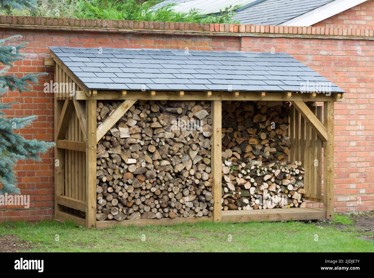 Wood shed, large log store filled with firewood, timber construction with a slate roof, UK Stock Photo