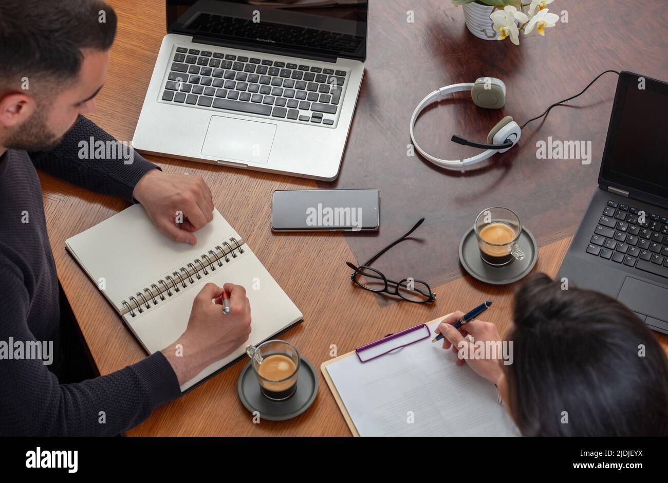 Two business people sitting at the office desk using laptop, man and woman working a project together. Teamwork, modern creative office concept, above Stock Photo