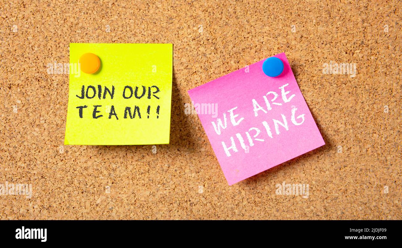 We Are Hiring in pink post it, Join Our Team in yellow one, on bulletin board cork background. Business vacancy text message, advertise, staff wanted Stock Photo