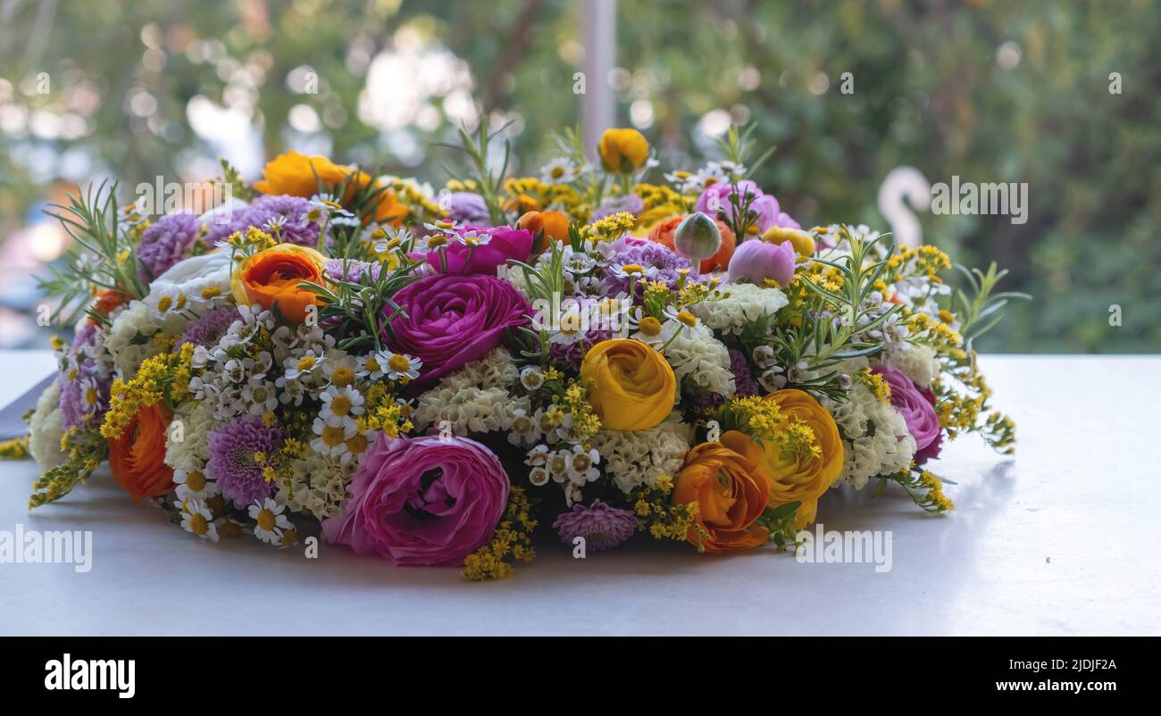 Women or Mothers day celebration, flower wreath bouquet decoration. Fresh colorful wild flowers and herbs on a marble table, close up. Spring, garden Stock Photo
