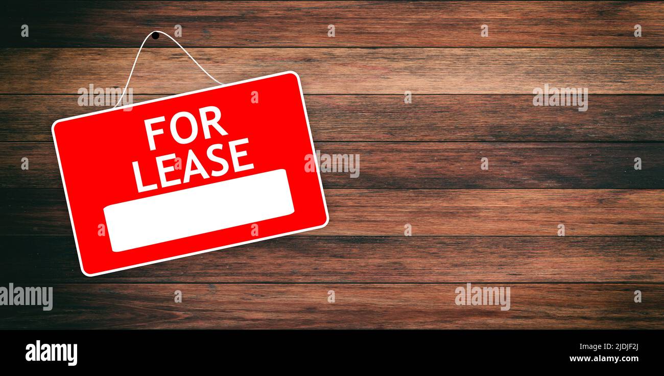 FOR LEASE red sign with white word on empty wooden background, advertising template. Label for real estate hiring hanged on wood surface, marketing fr Stock Photo