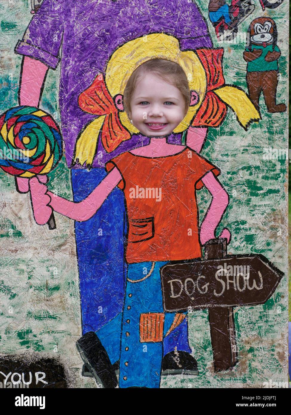 Young child at head in hole photo board at a fair, Cornwall, UK Stock Photo