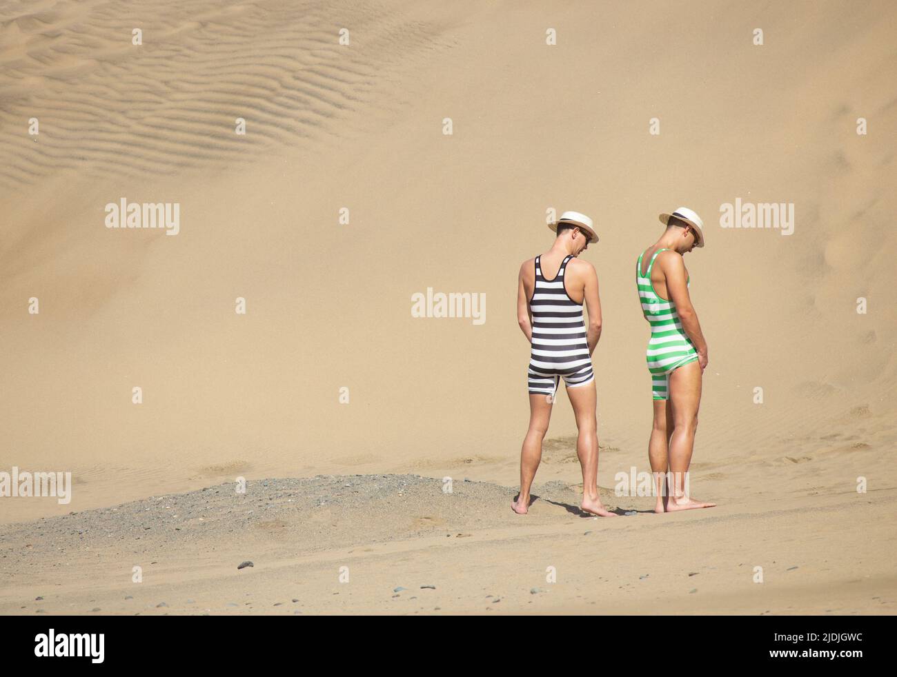 Men in fancy dress urinating, peeing, pissing on beach in Spain Stock Photo