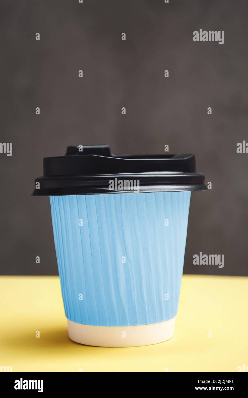 Blue paper cup with takeaway coffee. Container on a yellow and dark ...