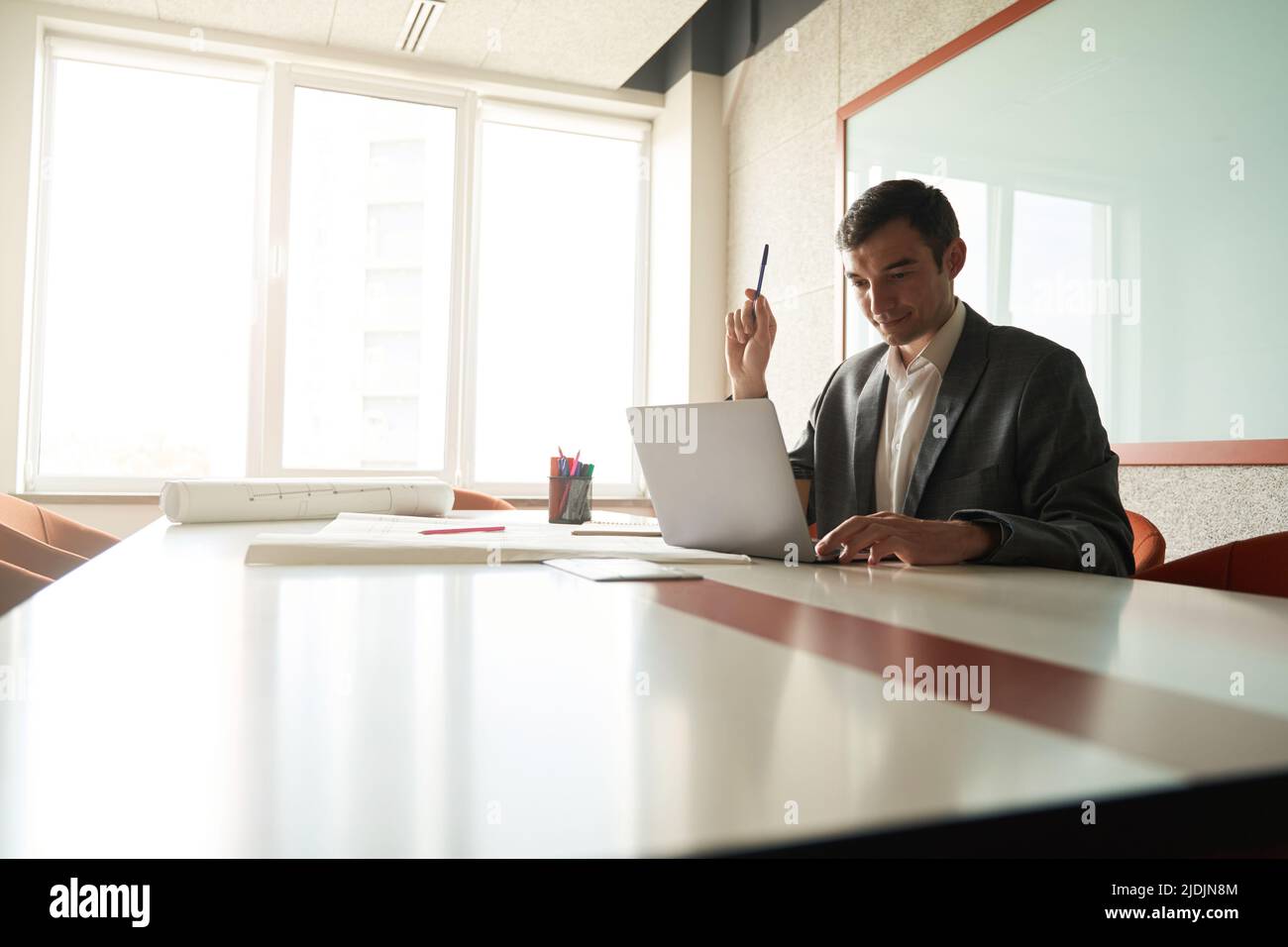 Designer holding pencil while working on laptop at table Stock Photo