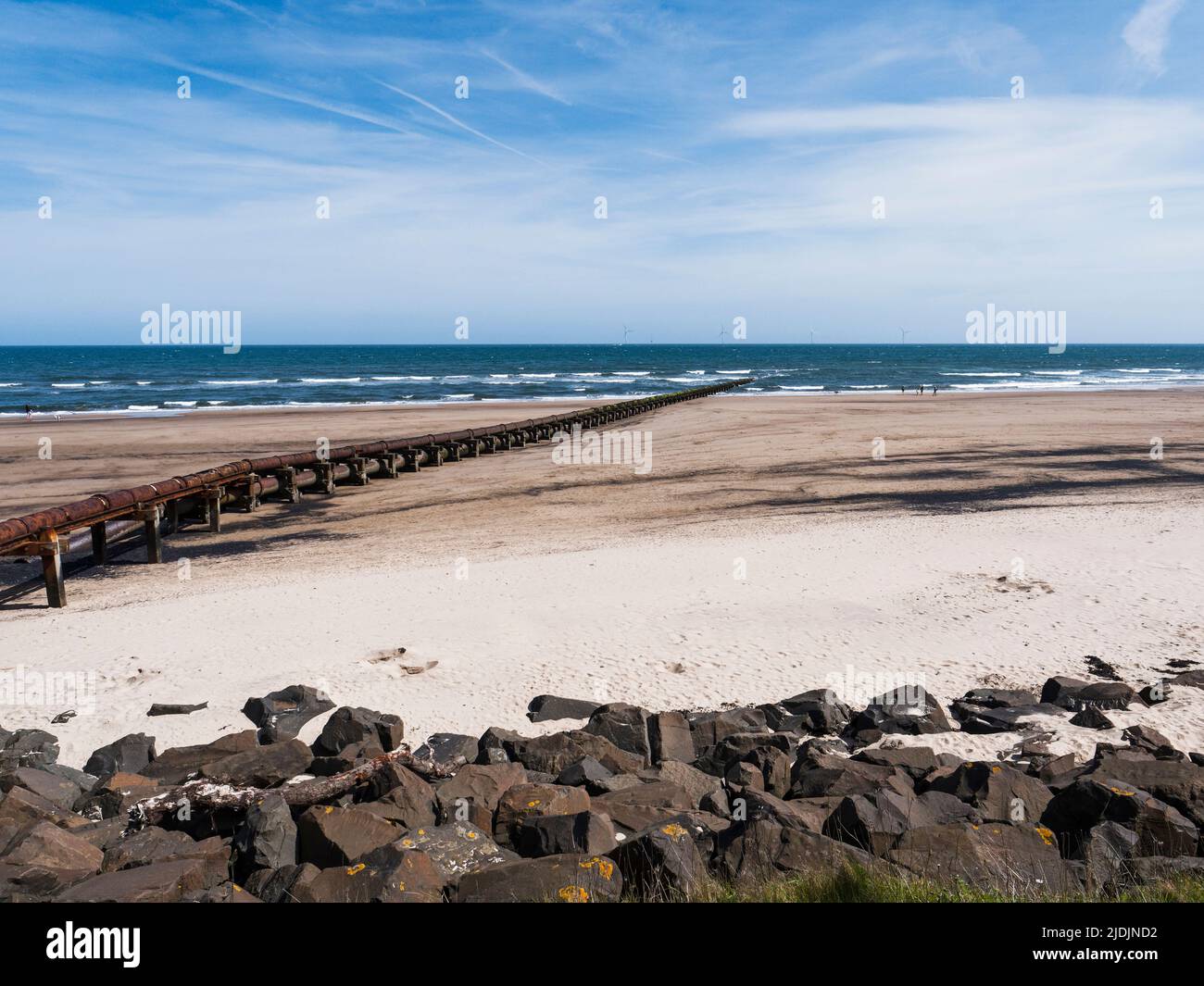 Cambois beach with rocks to prevent erosion and old sewage pipeline. Stock Photo