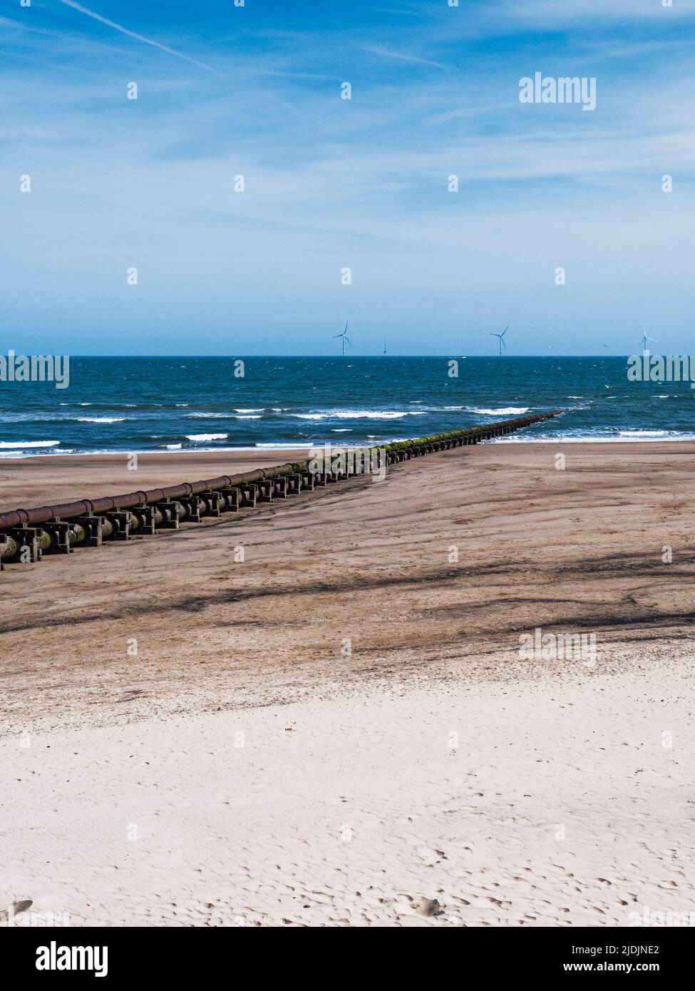 Cambois beach with old sewage pipeline and wind turbines. Stock Photo