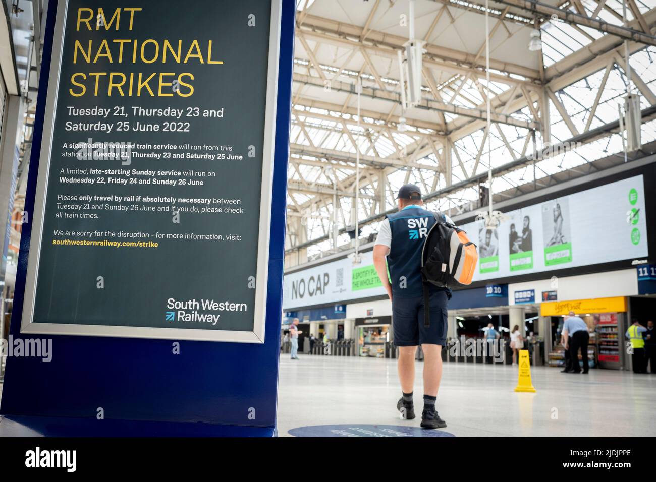 An employee of South Western Railway walks through Waterloo station's main concourse on the first day of the UK's rail strike, when railway and London Underground workers with the RMT union have taken industrial action, the most disruptive rail strike across England, Scotland and Wales for thirty years, on 21st June 2022, in London, England. Stock Photo