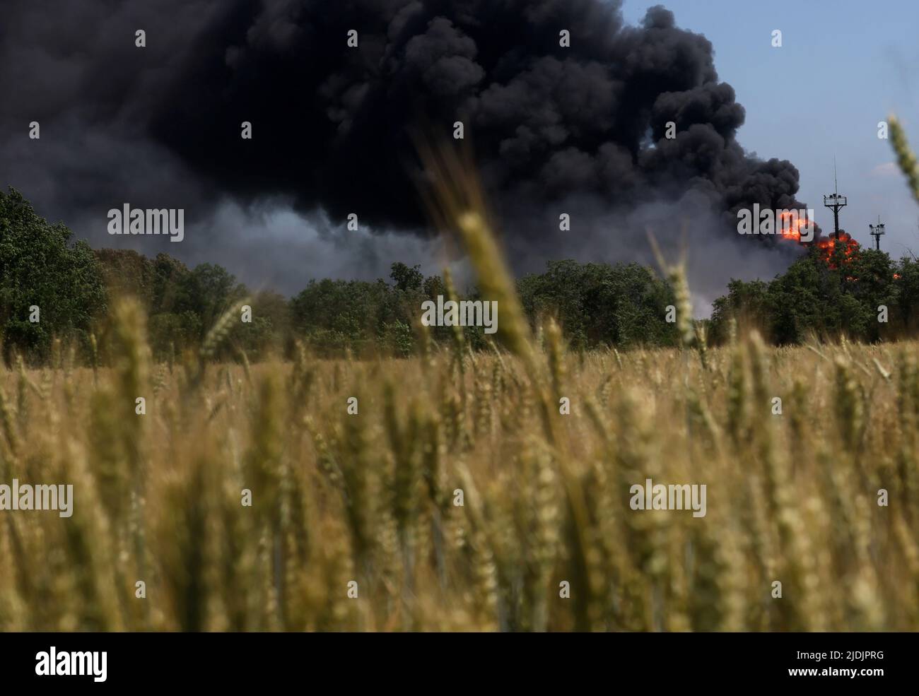 A fire from a gas processing plant continues to burn behind a field of wheat after the plant was hit by shelling a few days prior in Andriivka in the Kharkiv region as Russia's attack on Ukraine continues in Ukraine, June 21, 2022. REUTERS/Leah Millis Stock Photo