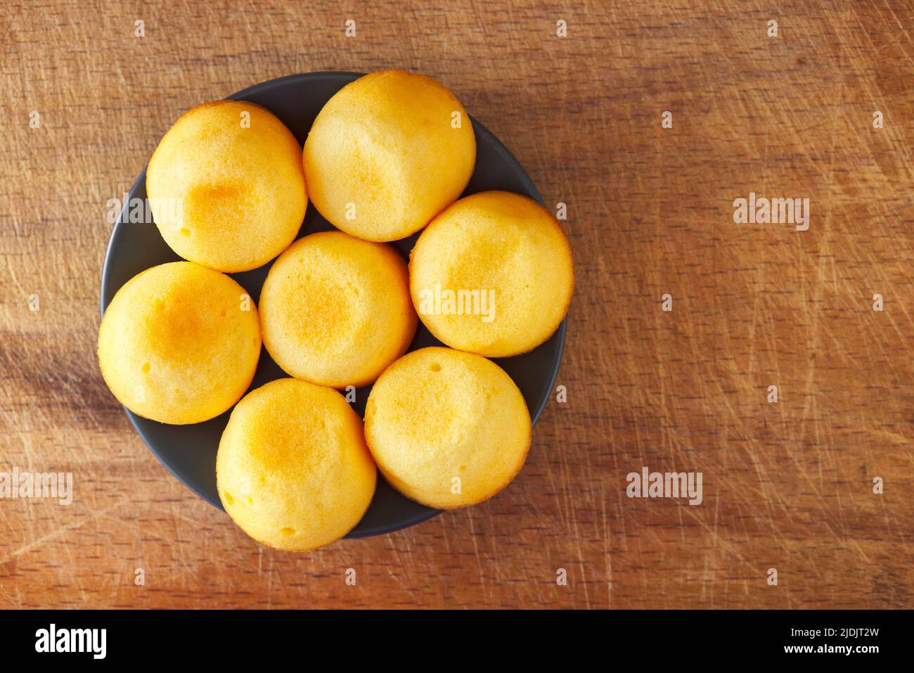 Small cakes on the plate on a wooden rustic background - top view Stock Photo