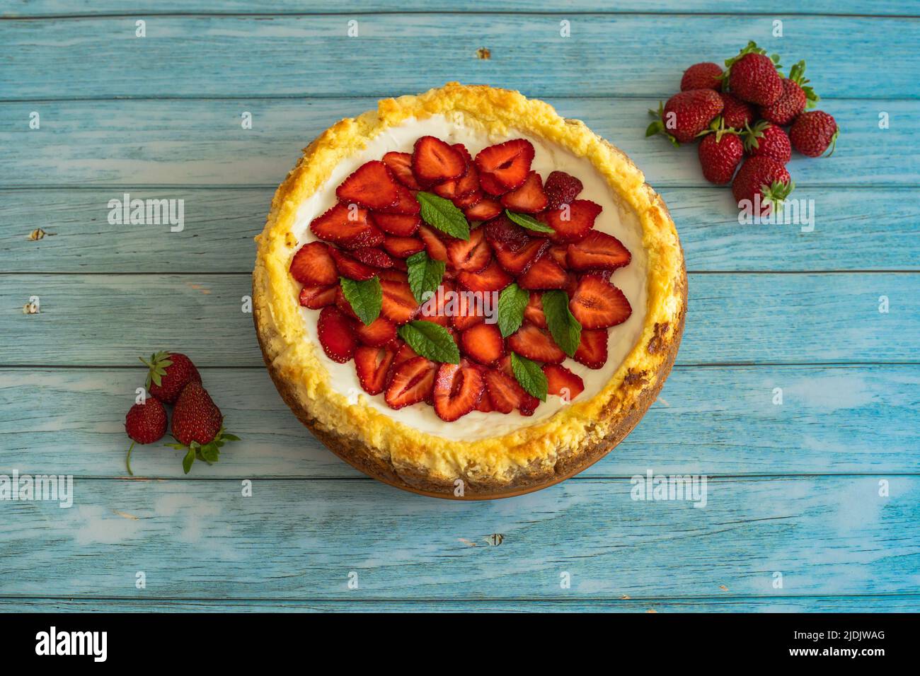 Strawberry homemade cake on wooden table.Delicious cheesecake with strawberries decorated with mint leaves.Top view.Healthy organic summer berry Stock Photo