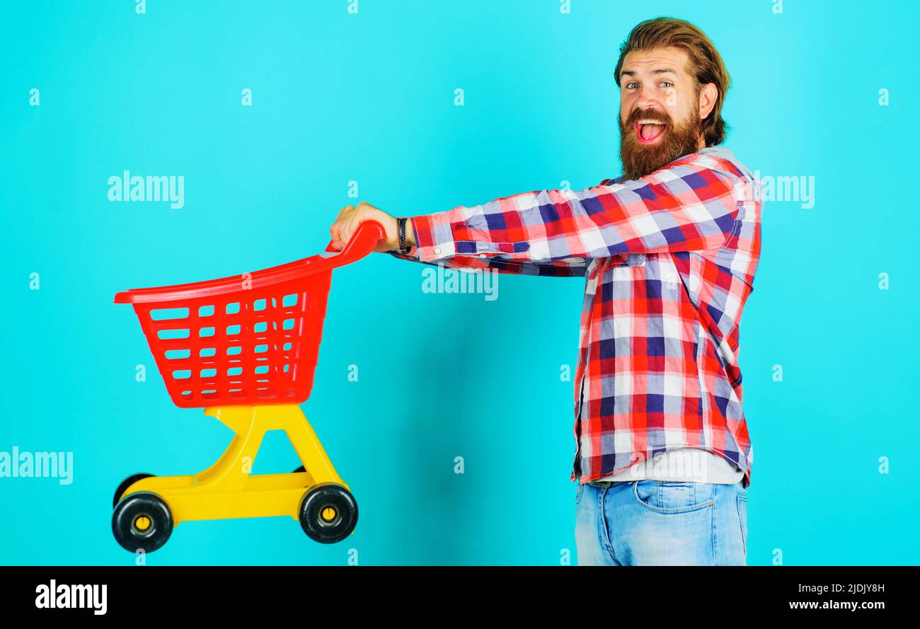 Supermarket. Happy bearded man with empty shopping cart or trolley. Grocery store. Buying spree. Stock Photo