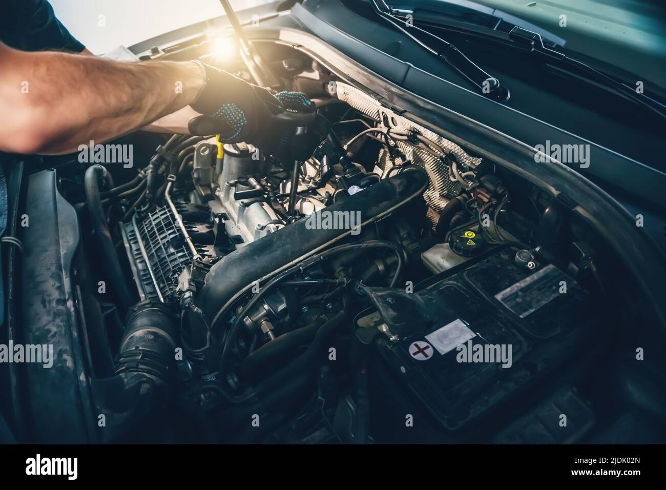 Serviceman changes spark plugs in modern turbocharged engine. Timely maintenance and replacement of consumables in car. Stock Photo