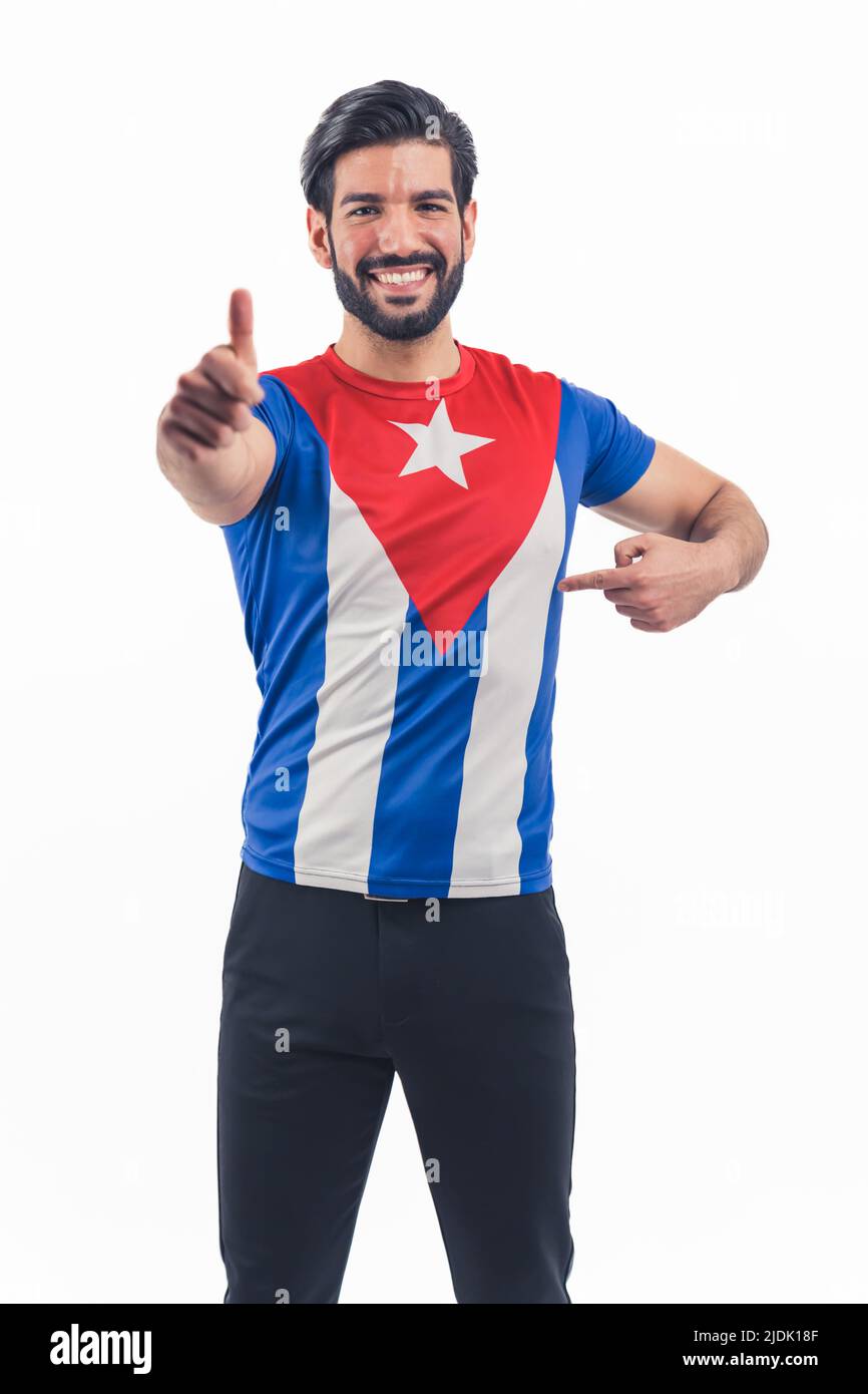 Full-length portrait of Latin guy promoting his t-shirt with Cuba flag in studio isolated on white background. High quality photo Stock Photo