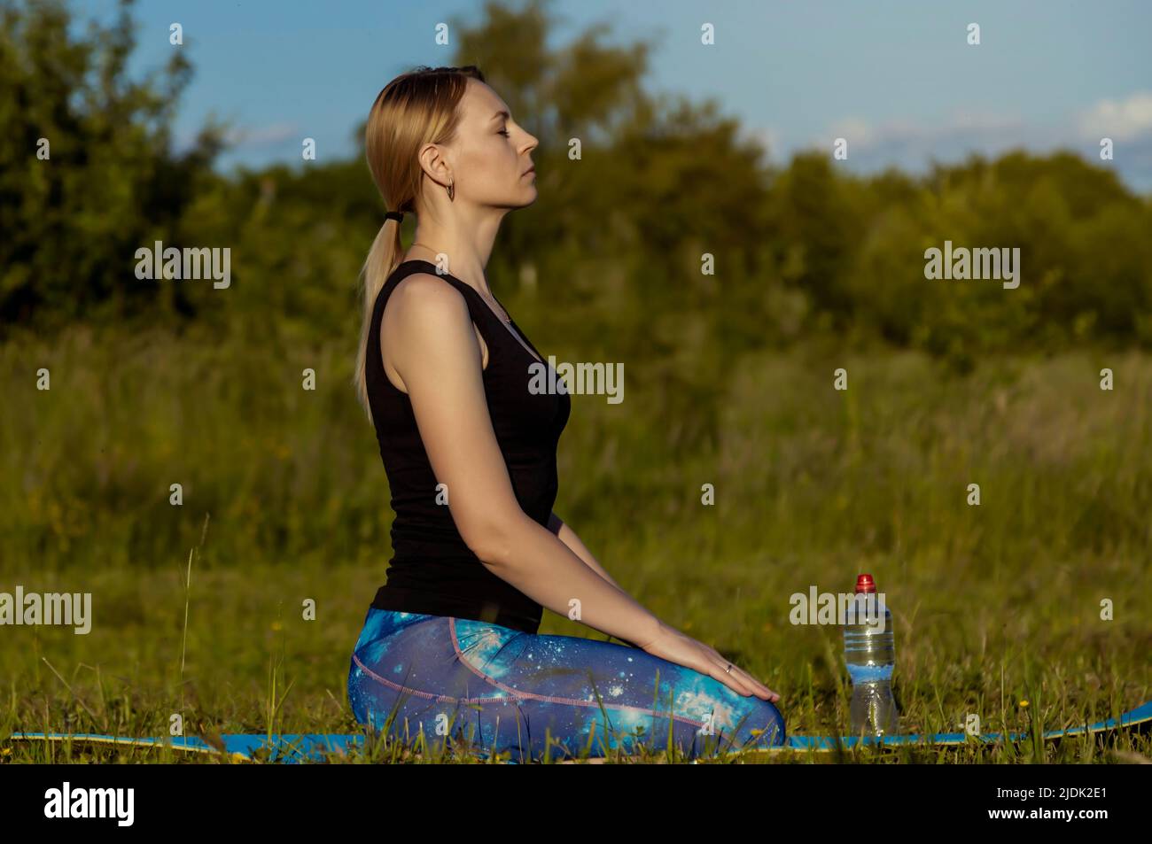 Healthy Lifestyle. Young woman meditates on a yoga mat at sunset. Training and training in the fresh air. Stock Photo