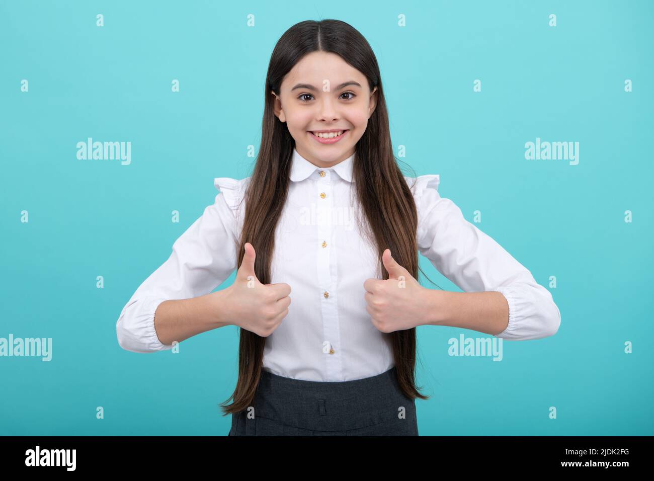 Optimistic cool teenager child girl with thumb up isolated on yellow background. Little schoolgirl student. Stock Photo