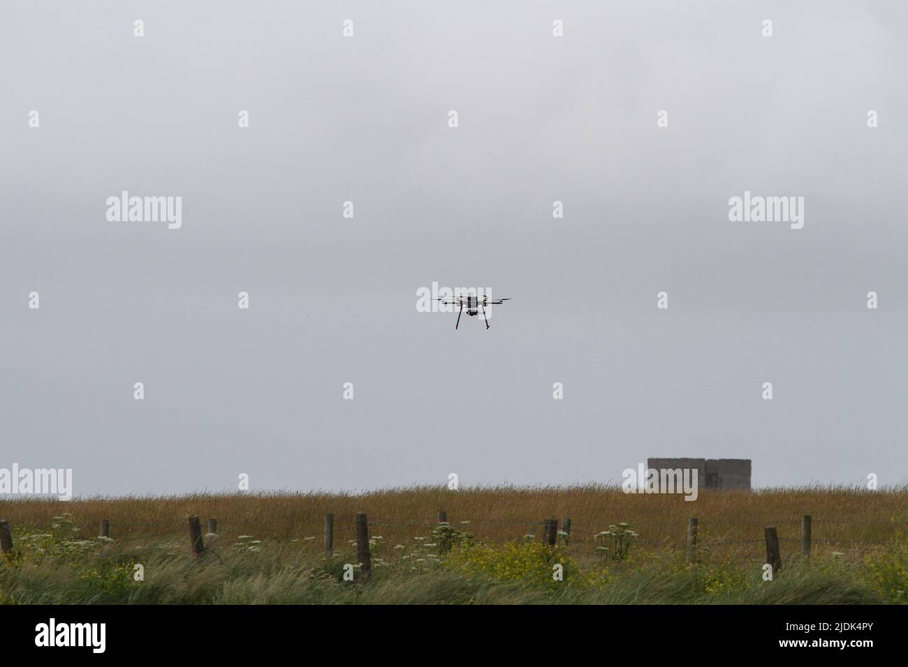UK Black drone with lights and camera hovering over field and fences in 2015. Stock Photo