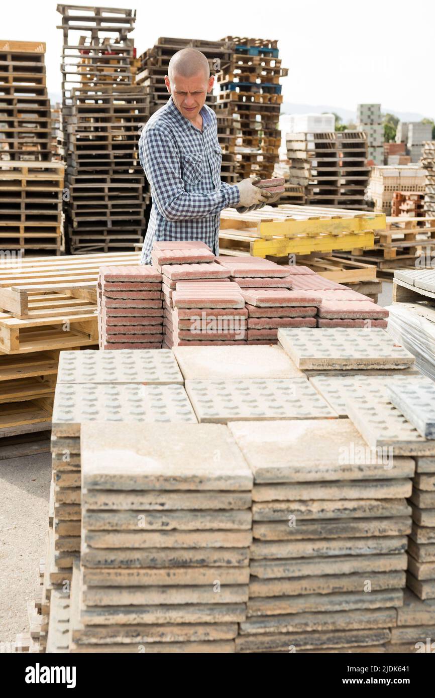 Warehouse employee puts paving slabs on pallet Stock Photo Alamy