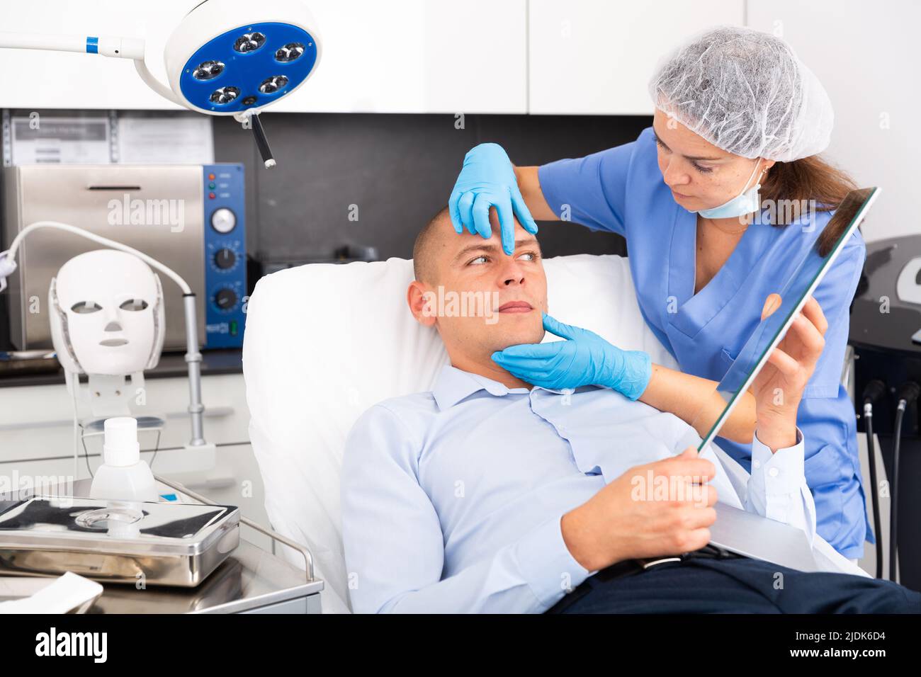 Female cosmetician explaining man hardware facial procedure in ...
