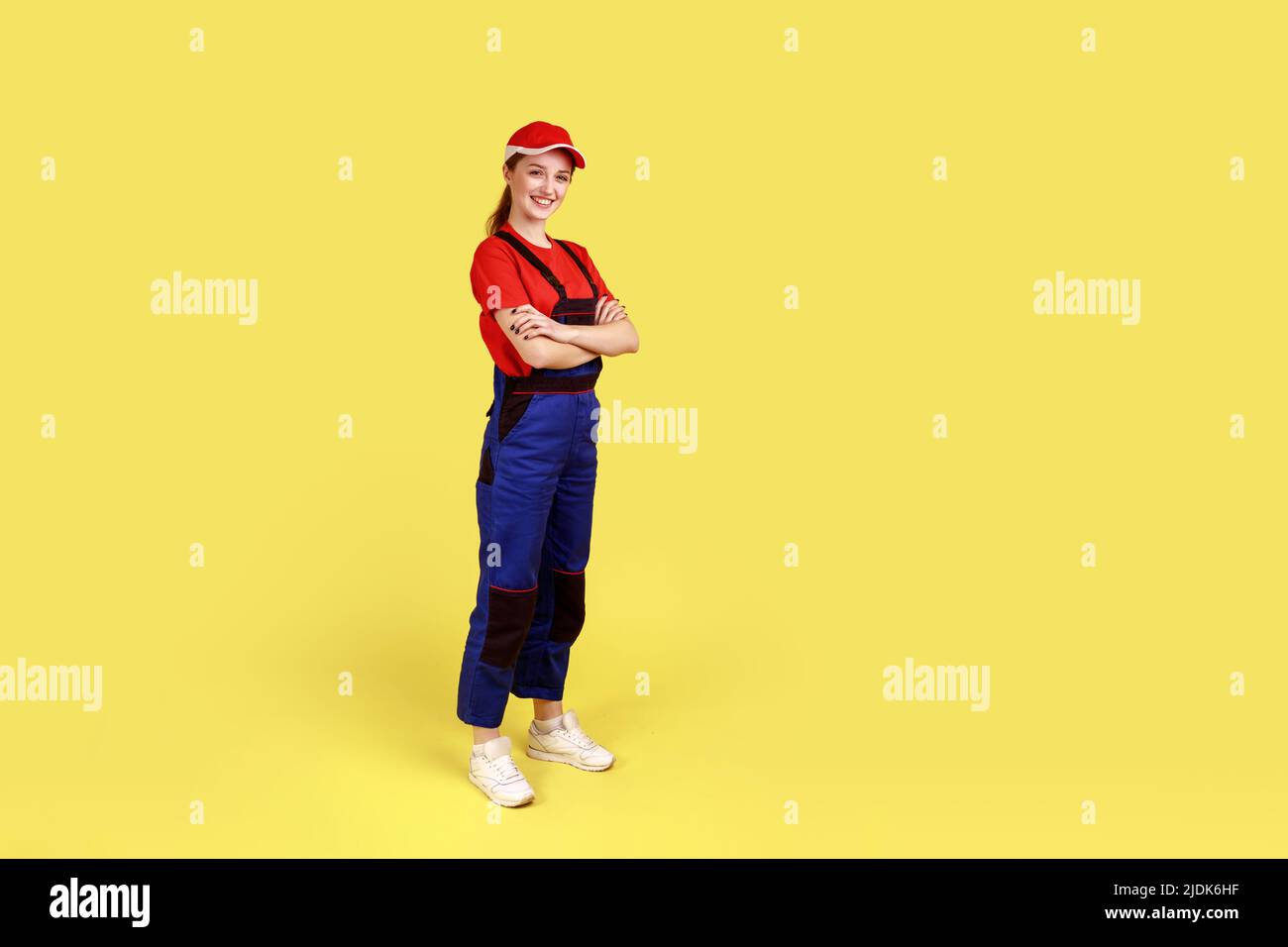 Full length portrait of happy smiling handy woman standing with crossed ...