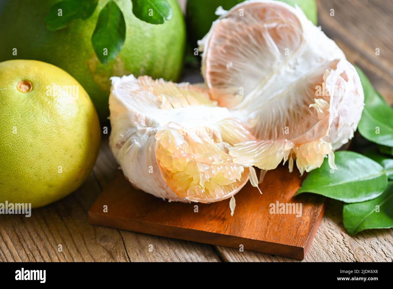 Fresh green pomelo peeled and leaf frome pomelo tree , pomelo fruit on wooden plate background