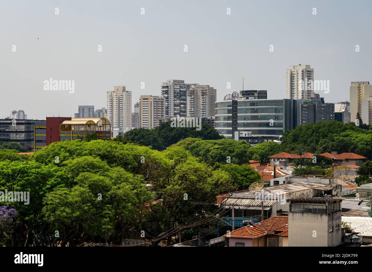 Cityscape view of Agua Branca and Barra funda districts with many high rise buildings and tall green vegetation trees in sight under sunny blue sky. Stock Photo