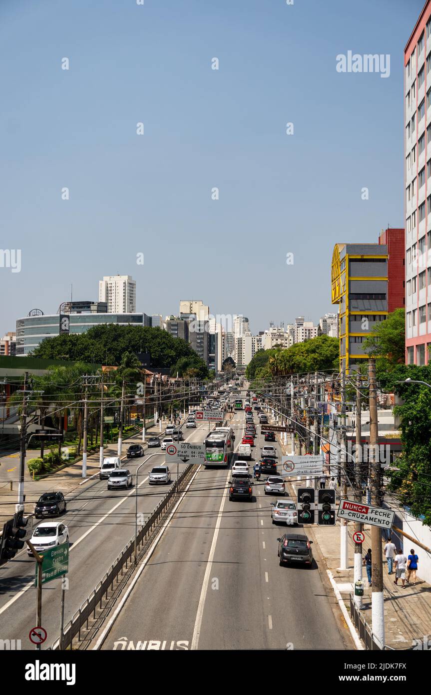 Heavy traffic passing by both ways of Francisco Matarazzo avenue in Agua Branca district with lots of skyscrapers at the back under sunny blue sky. Stock Photo
