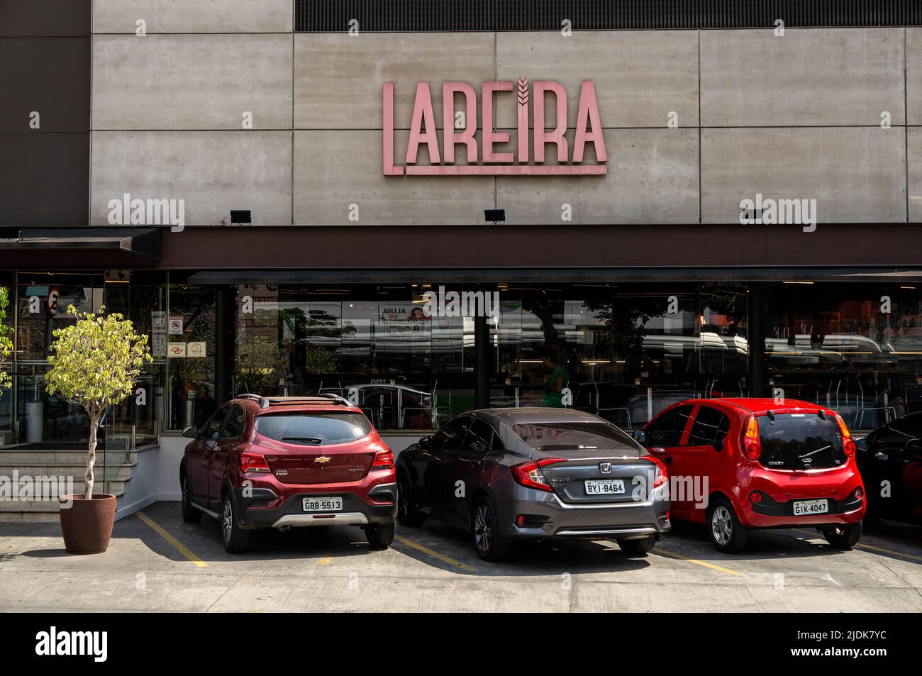 Facade and entrance of Lareira bakery shop with some cars parked at it in a sunny day. Shop located at Sumare avenue, at the corner of Iperoig street. Stock Photo