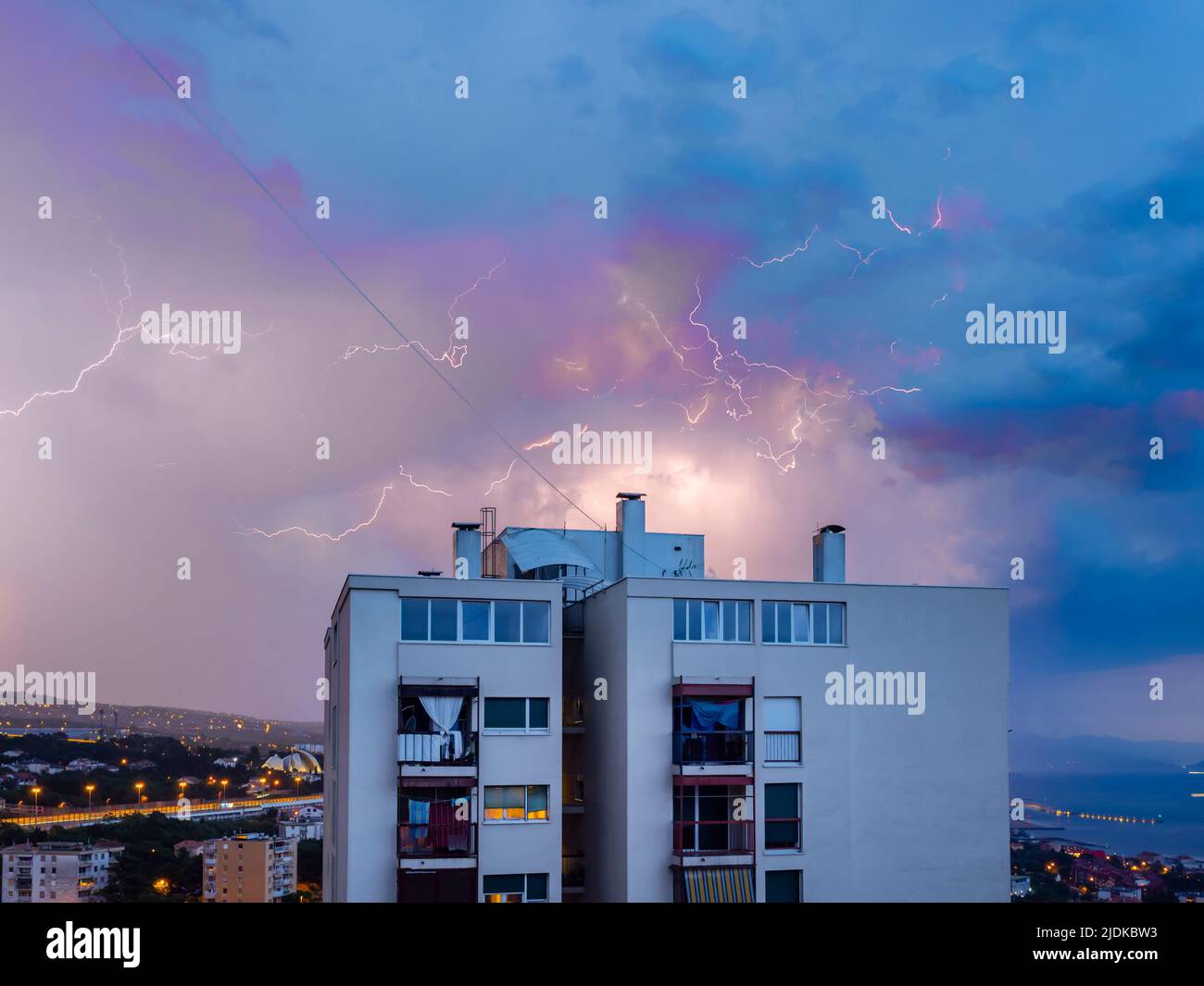 Thunder lightning dancing on wire in sky above building Stock Photo