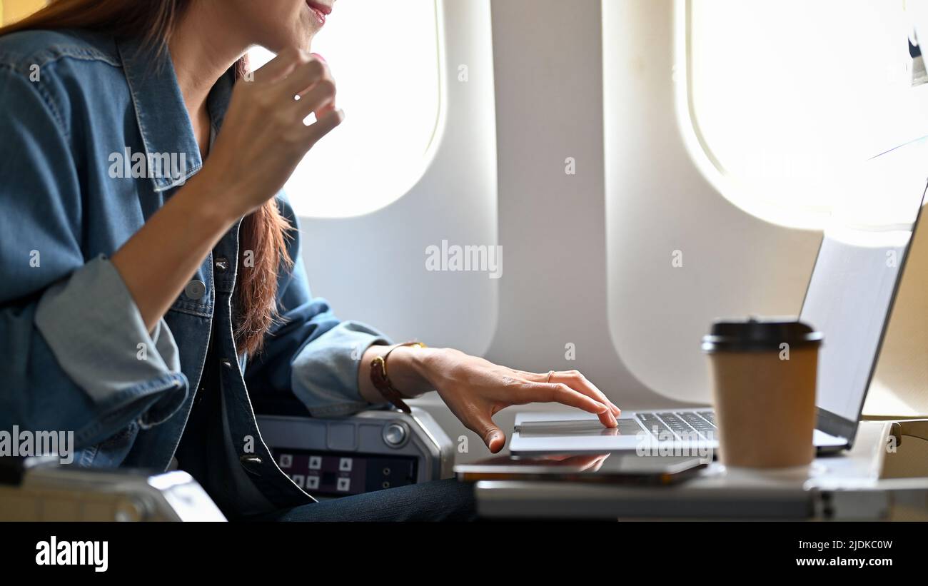 Attractive young asian female freelancer remote working on the plane