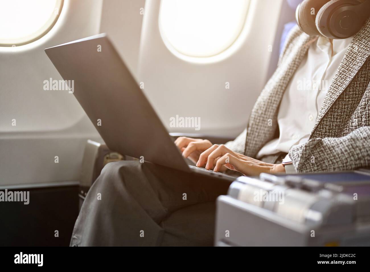 Gorgeous businesswoman on the plane in a business class seat, using laptop computer to work on her business project. Urban lifestyle with transportati Stock Photo