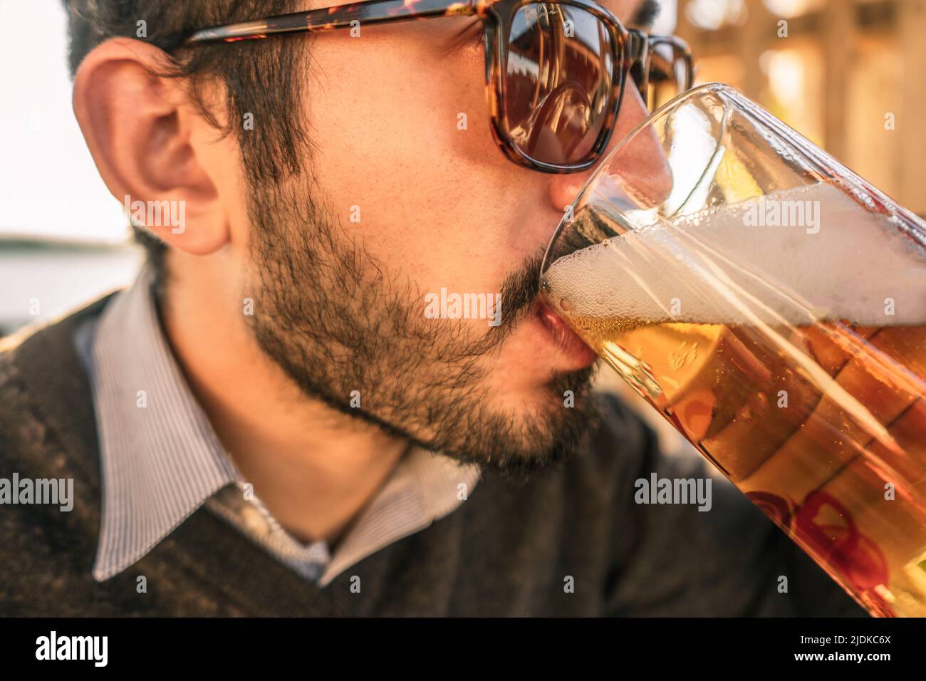 Young man with a beard and sunglasses drinking beer from a mug Stock Photo