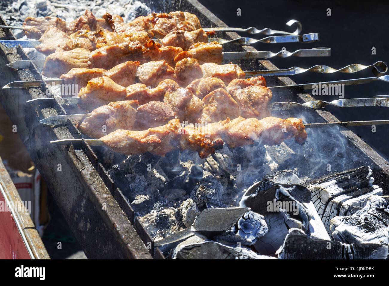 Folk authentic traditional national cuisine of mountain peoples in the form of shish kebab fried on an open fire with vegetables. Stock Photo