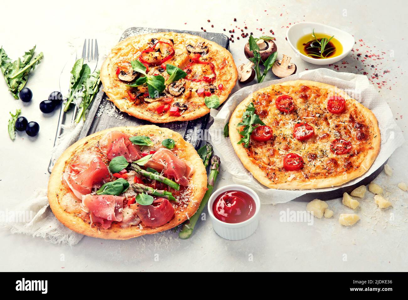 Various kinds of Italian pizza - Margherita, pepperoni, ham, mushrooms with basil, tomatoes, olive oil and cheese on white background. Top view. Stock Photo