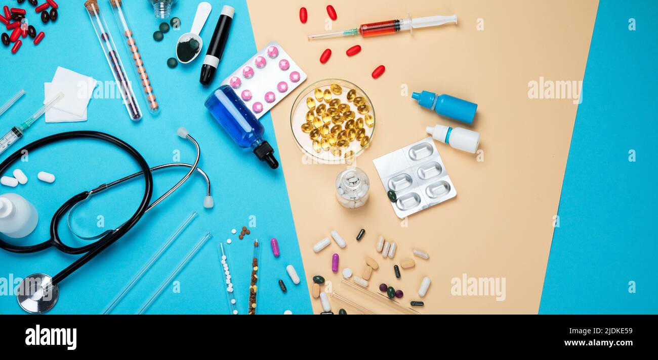 Various medical equipment, ampoules, pipette, drugs, tablets, capsules, spray on blue background. Top view, panorama with copy space. Stock Photo