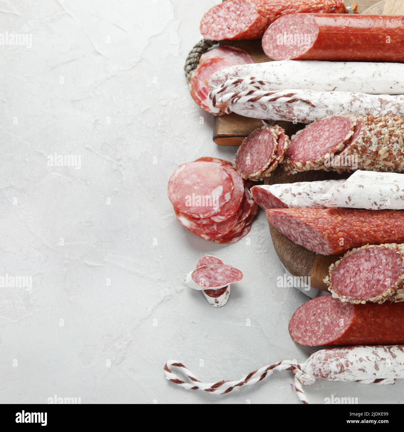 Sausages salami assortment on light background. Meat product made of finely chopped and seasoned meat. Flat lay, top view, copy space Stock Photo