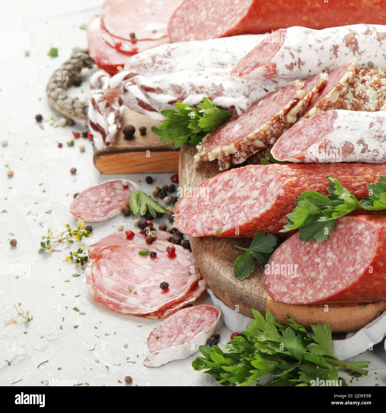 Sausages salami assortment on light background. Meat product made of finely chopped and seasoned meat. Stock Photo