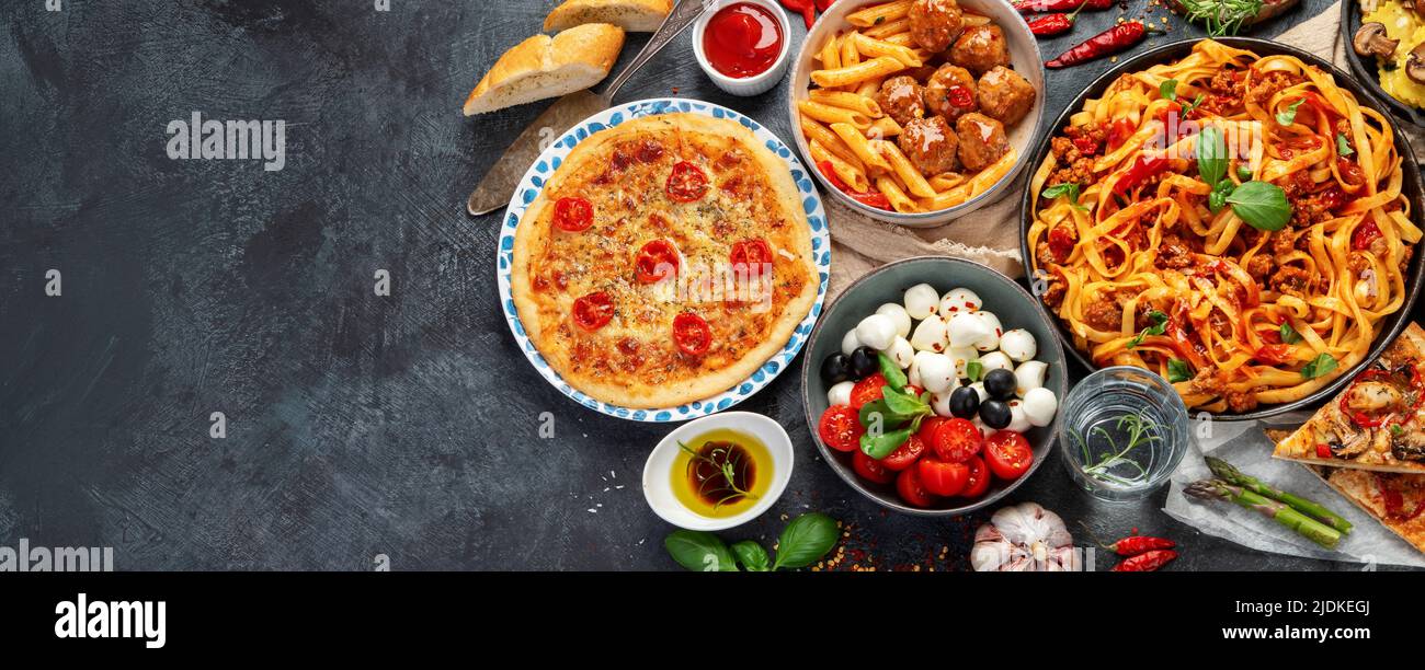 Italian food assortment on dark background. Traditional food concept. Dishes and appetizers of indeed cuisine. Flat lay, top view, copy space, panoram Stock Photo