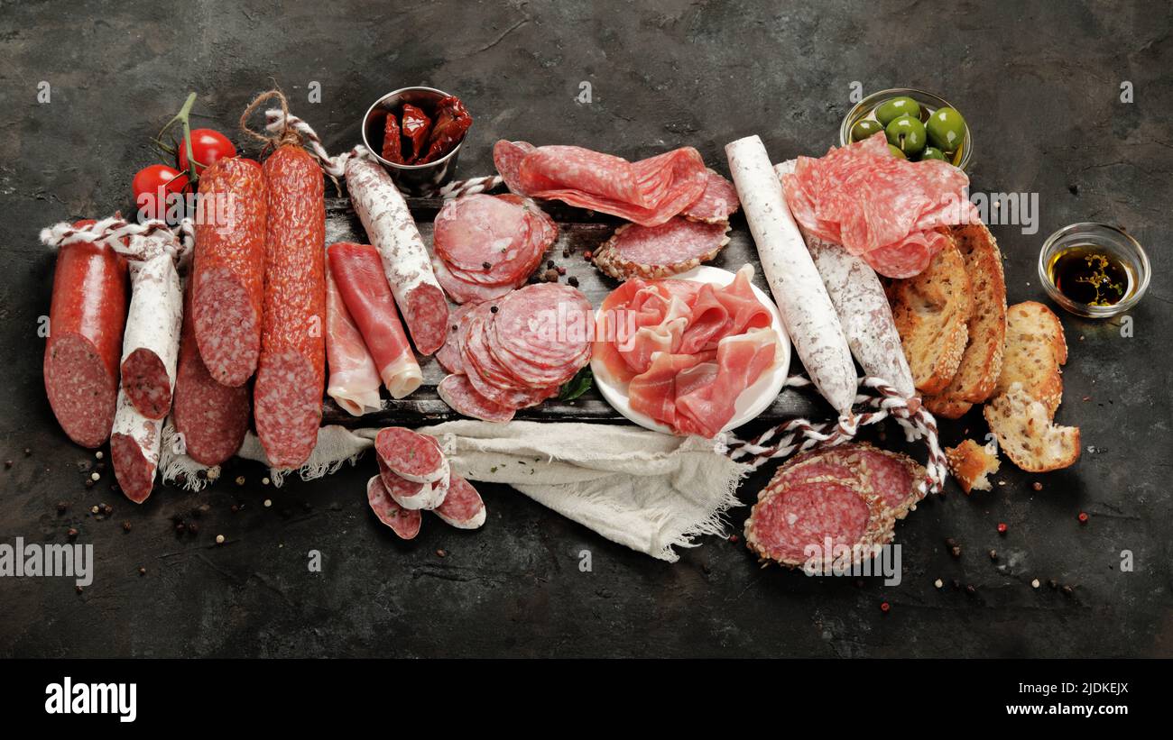 Sasusages assortment on dark background. Meat product made of finely chopped and seasoned meat. Stock Photo
