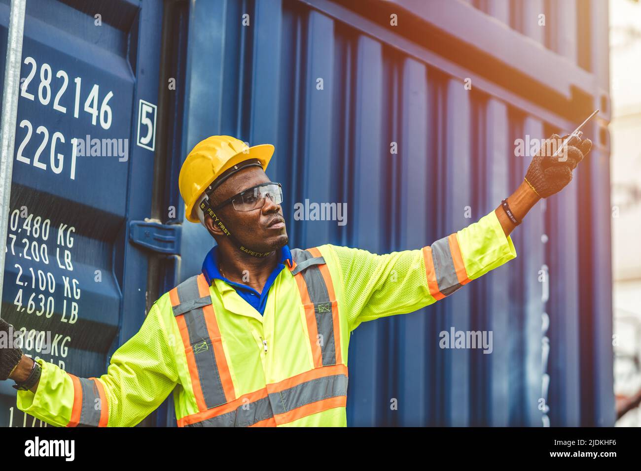 Foreman control loading Containers Cargo box freight ship for import export, black worker work in Container Cargo freight shipping Industry . Stock Photo