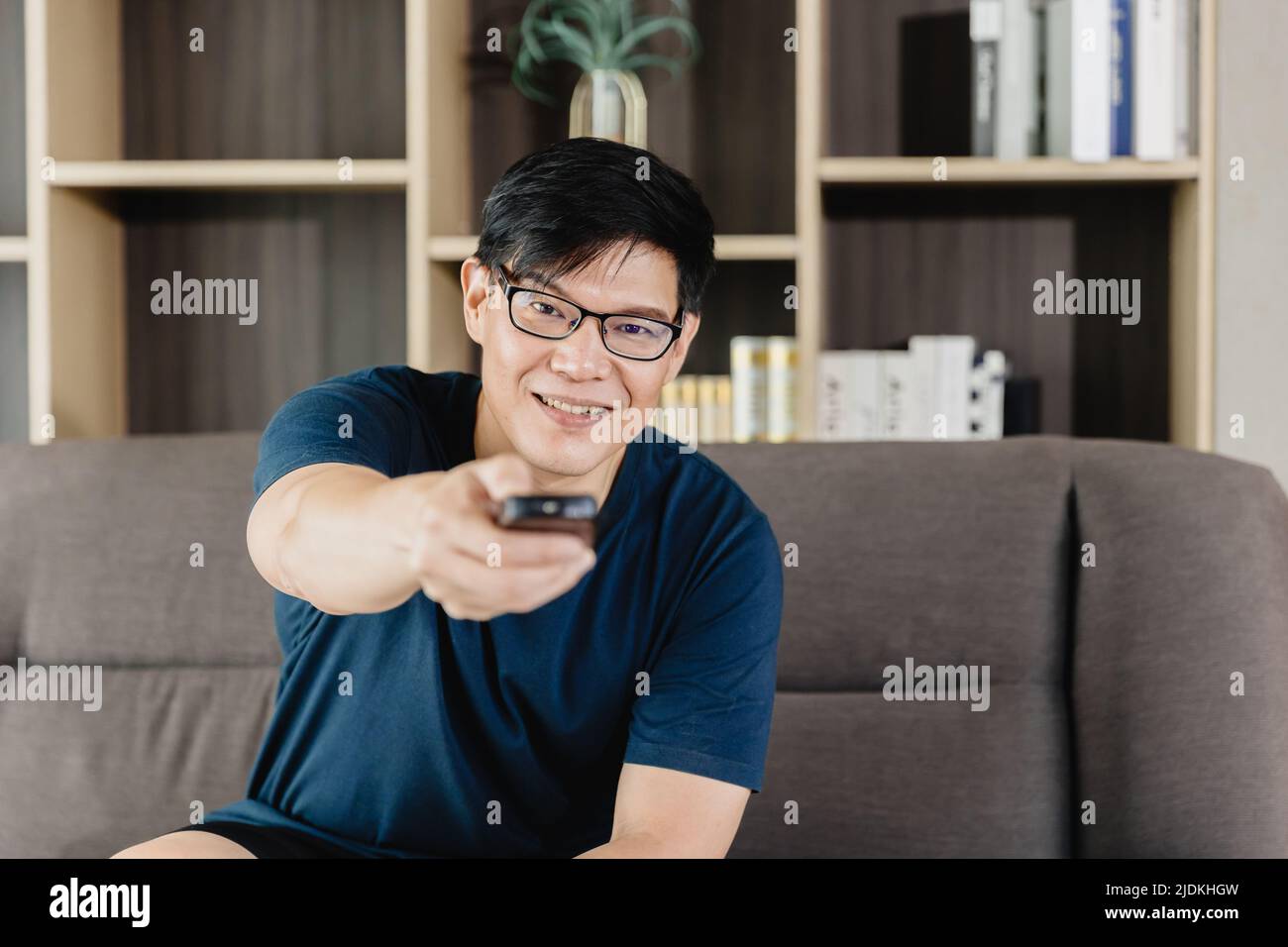 Man Happy Smile Pointing Tv Remote Control For Watching Home Entertainment Program At Holiday Weekend. Stock Photo