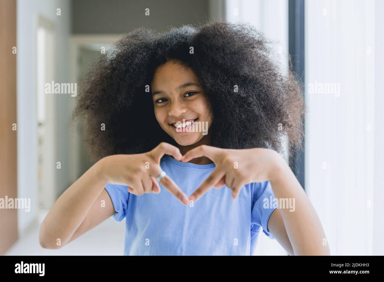 black teen girl afro hair happy smile with hand love heart sign. Stock Photo