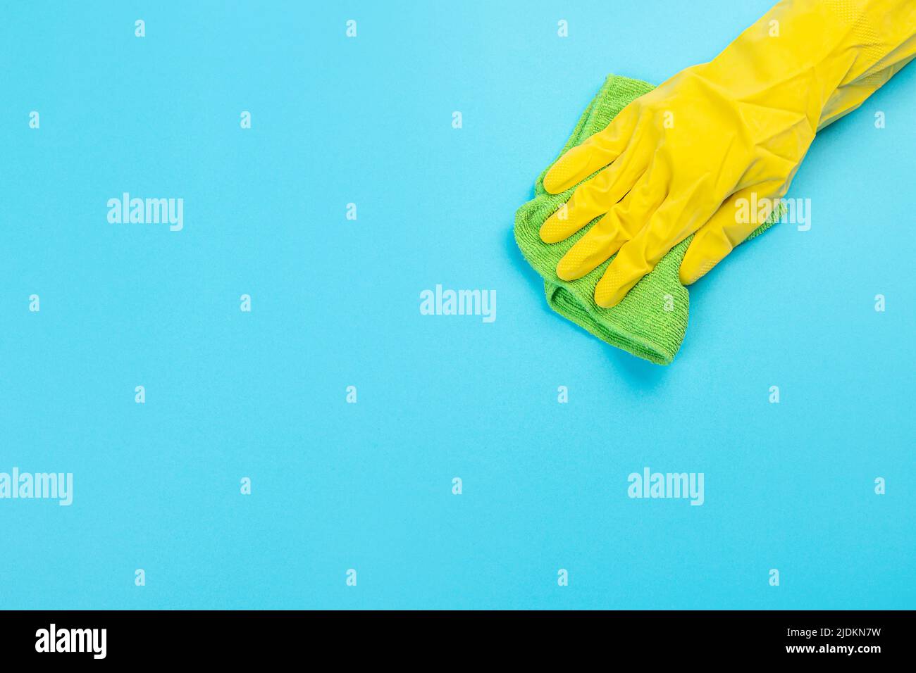 worker's hand in yellow rubber protective glove with micro fiber green sponge or washcloth. A maid or housewife takes care of the house. general or re Stock Photo