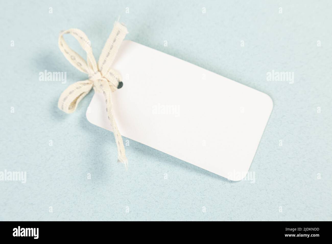 An empty white price tag lies on a gray-blue background with a soft shadow. Stock Photo