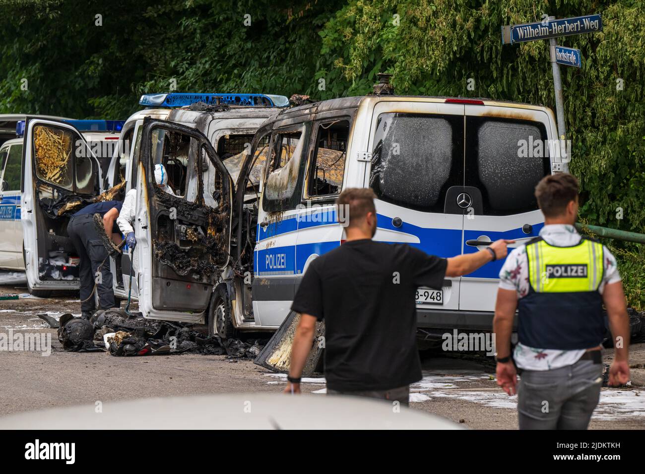 Munich, Germany. 22nd June, 2022. Forensics investigators work on police cars that burned out during the night. The team buses of the federal riot police are parked in front of a hotel where police officers are accommodated for the G7 summit. Investigators assume that the fire was caused by arson. Credit: Peter Kneffel/dpa/Alamy Live News Stock Photo
